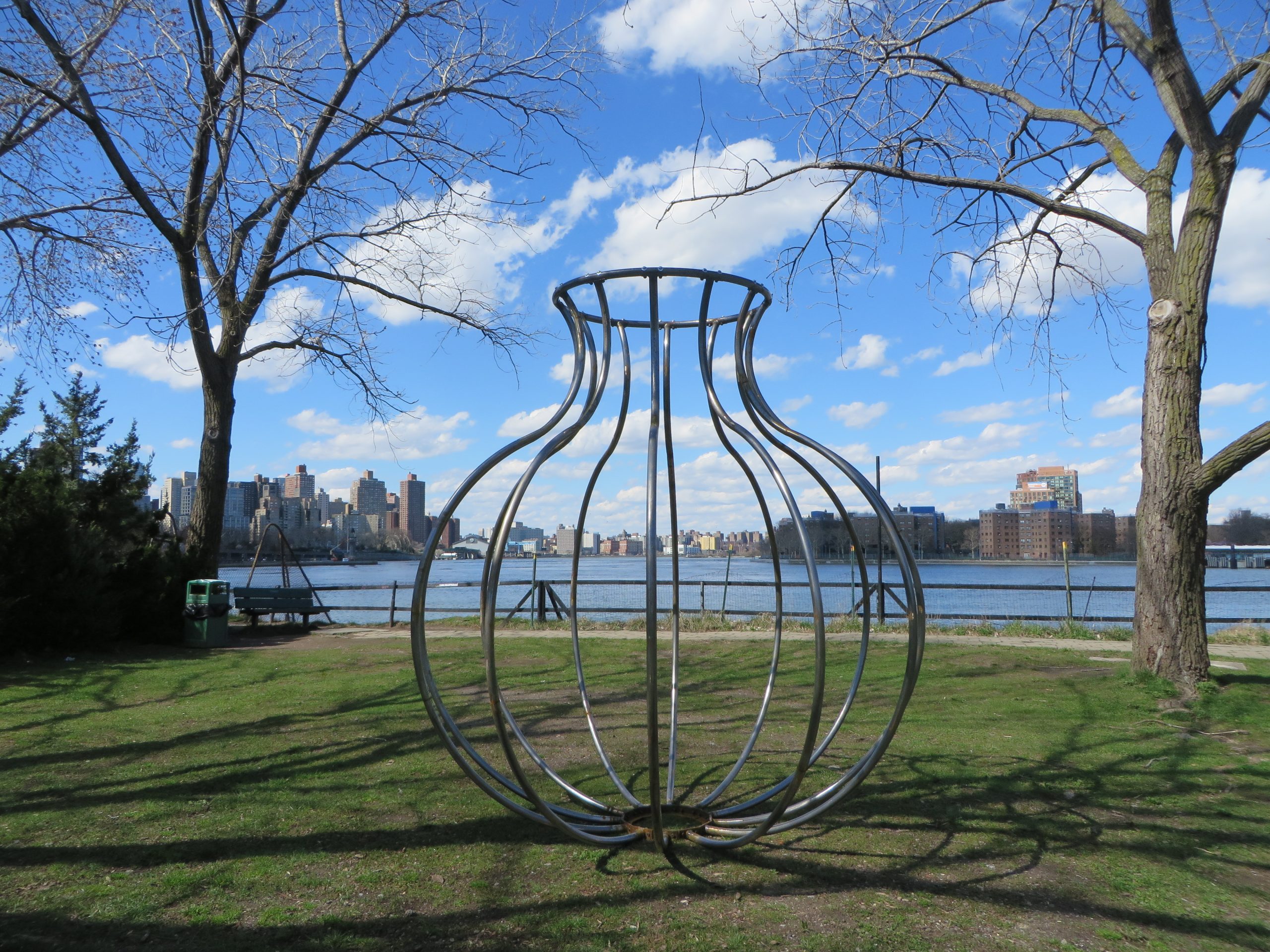 Maren Hassinger 9' steel linear sculpture, gourd-shape with the East River and city skyline behind it.